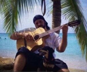 A man sitting on the beach playing guitar