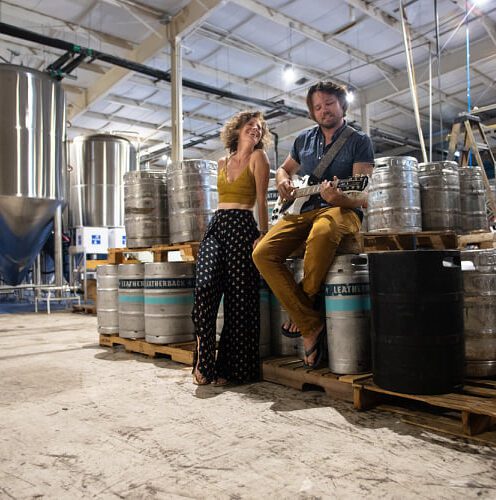 A man and woman sitting on top of barrels.
