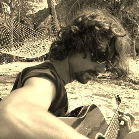 A man sitting on the beach playing an instrument.