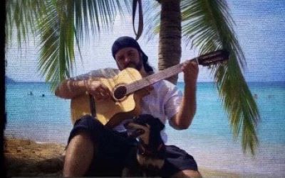 A man sitting on the beach playing an instrument.